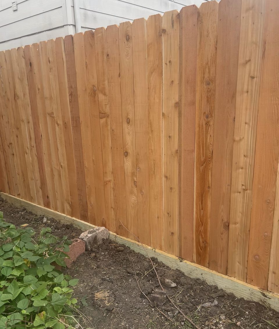 Close view of a new cedar fence section beside a house.
